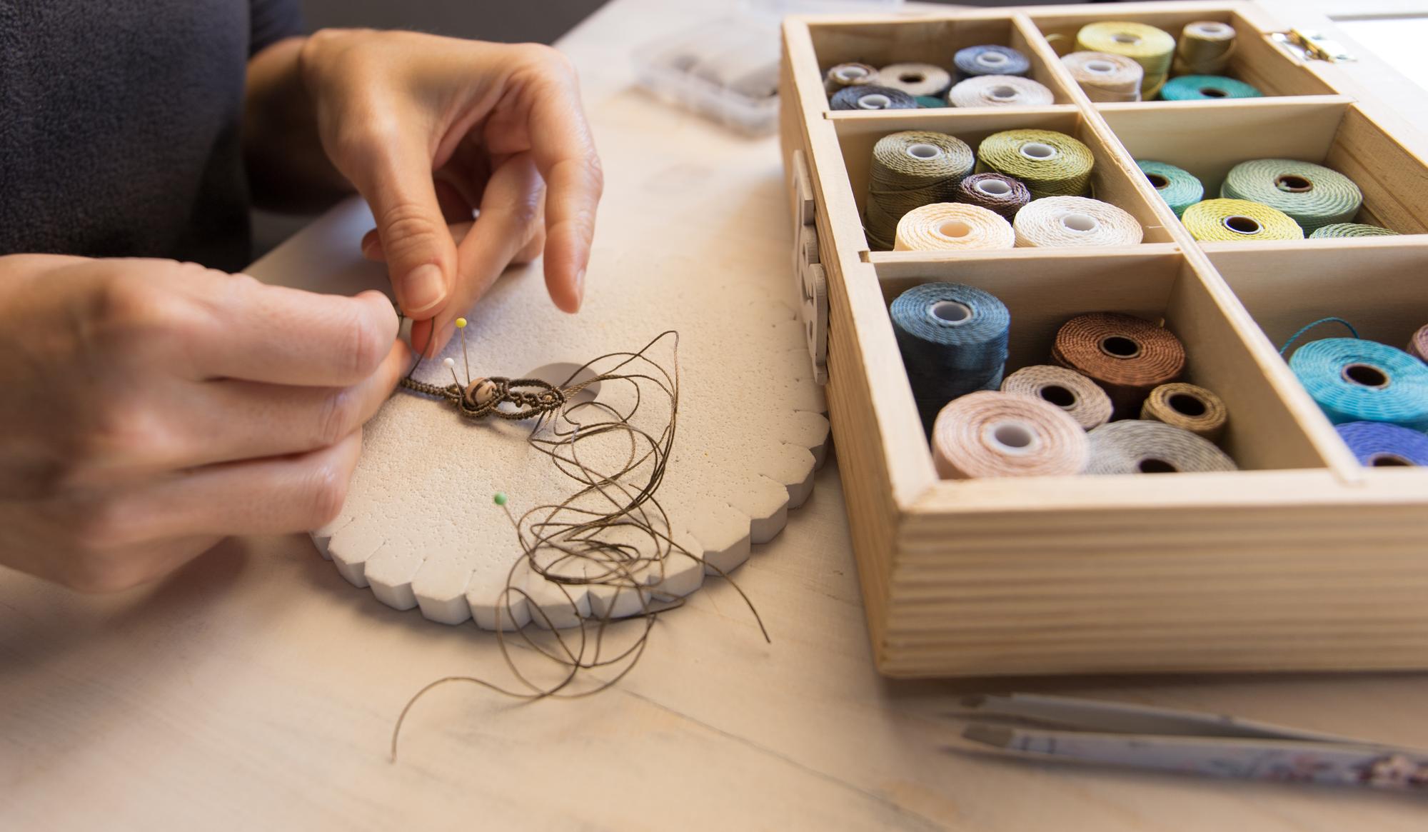 Artisan arranging embroidery threads and sketches on a table